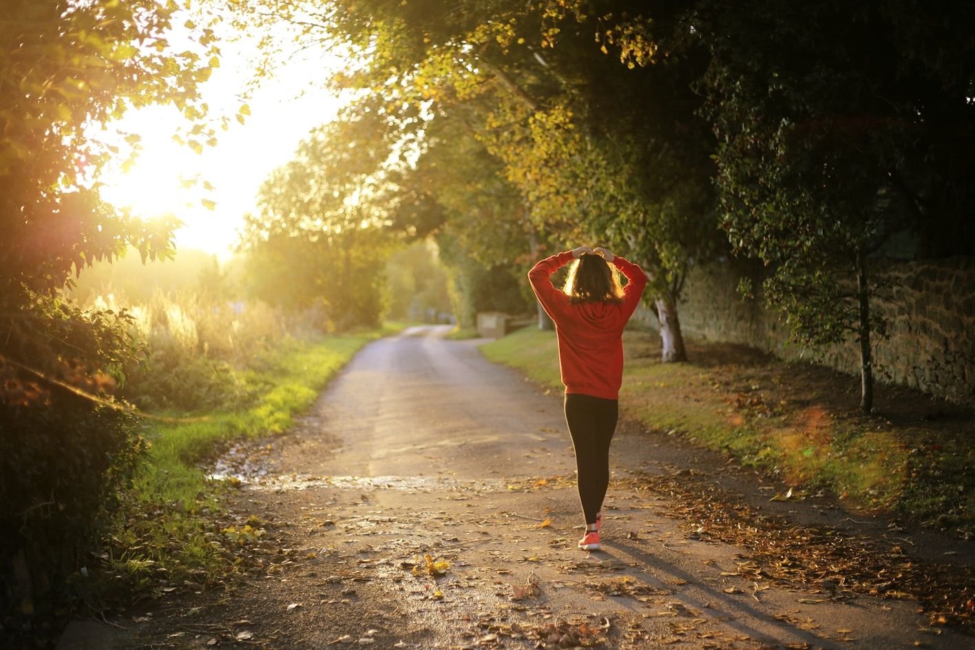 person walking down a country road with lush greenery on either side