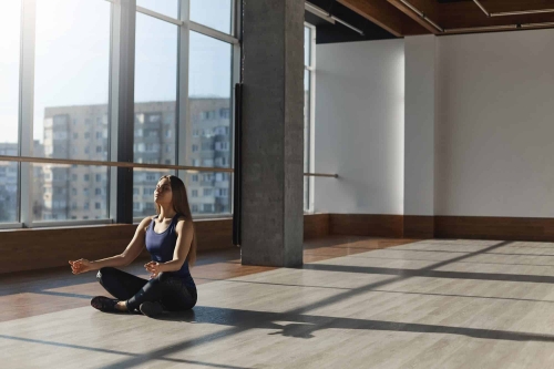 person meditating in a large room with floor to ceiling windows