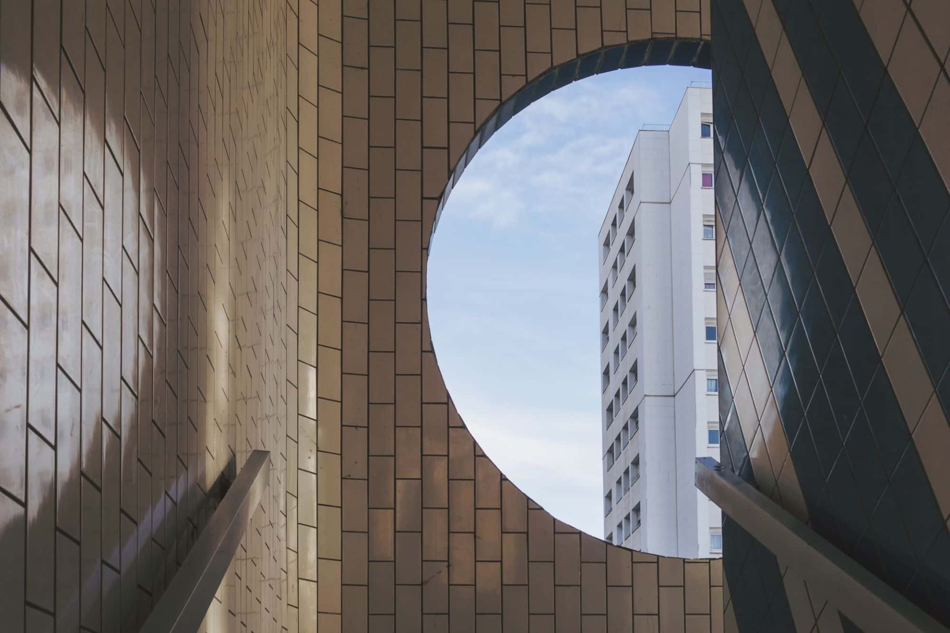 Round window in a stairwell looking out to blue skies.